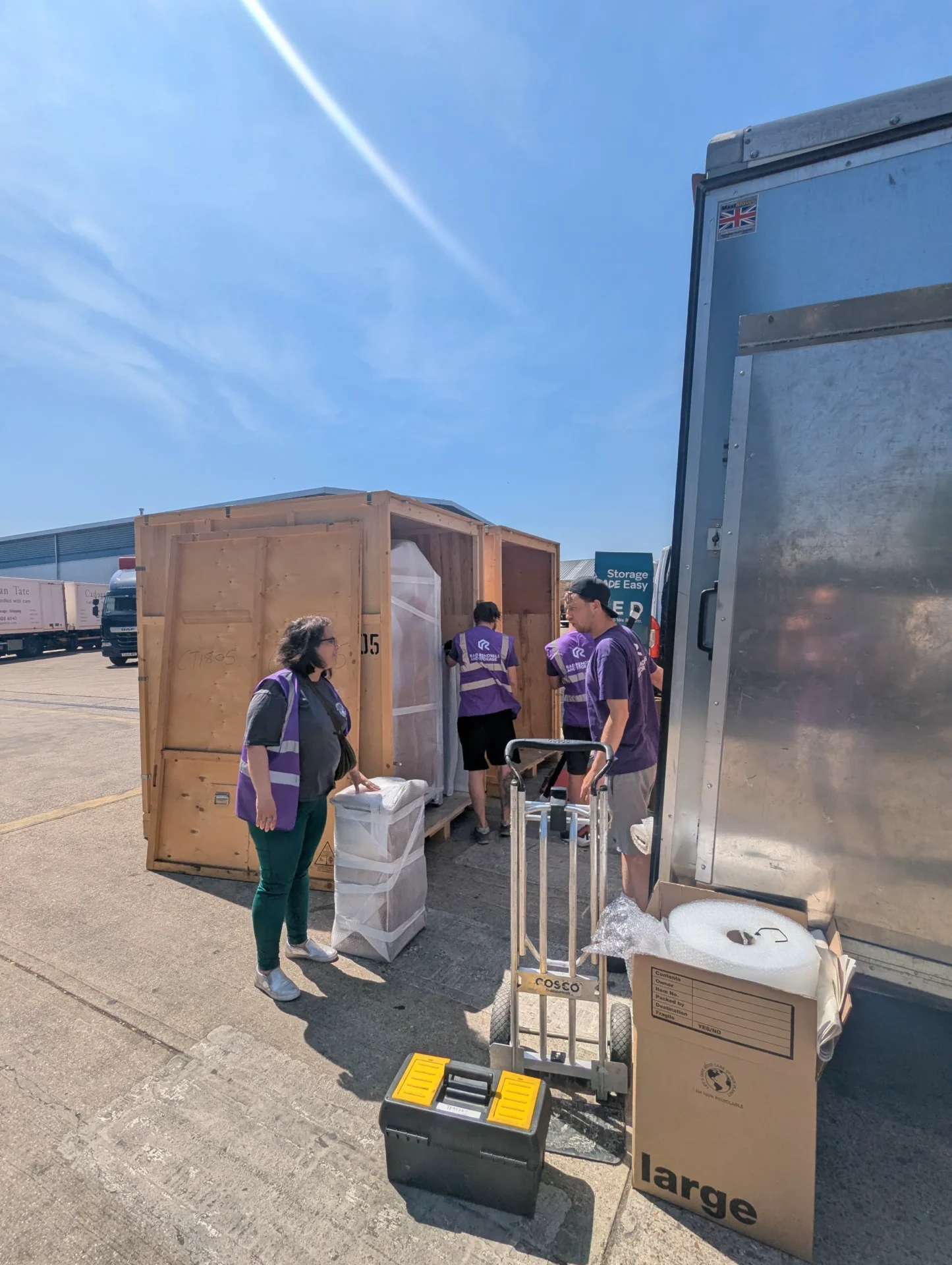Rad team member checking inventory list beside wooden storage containers